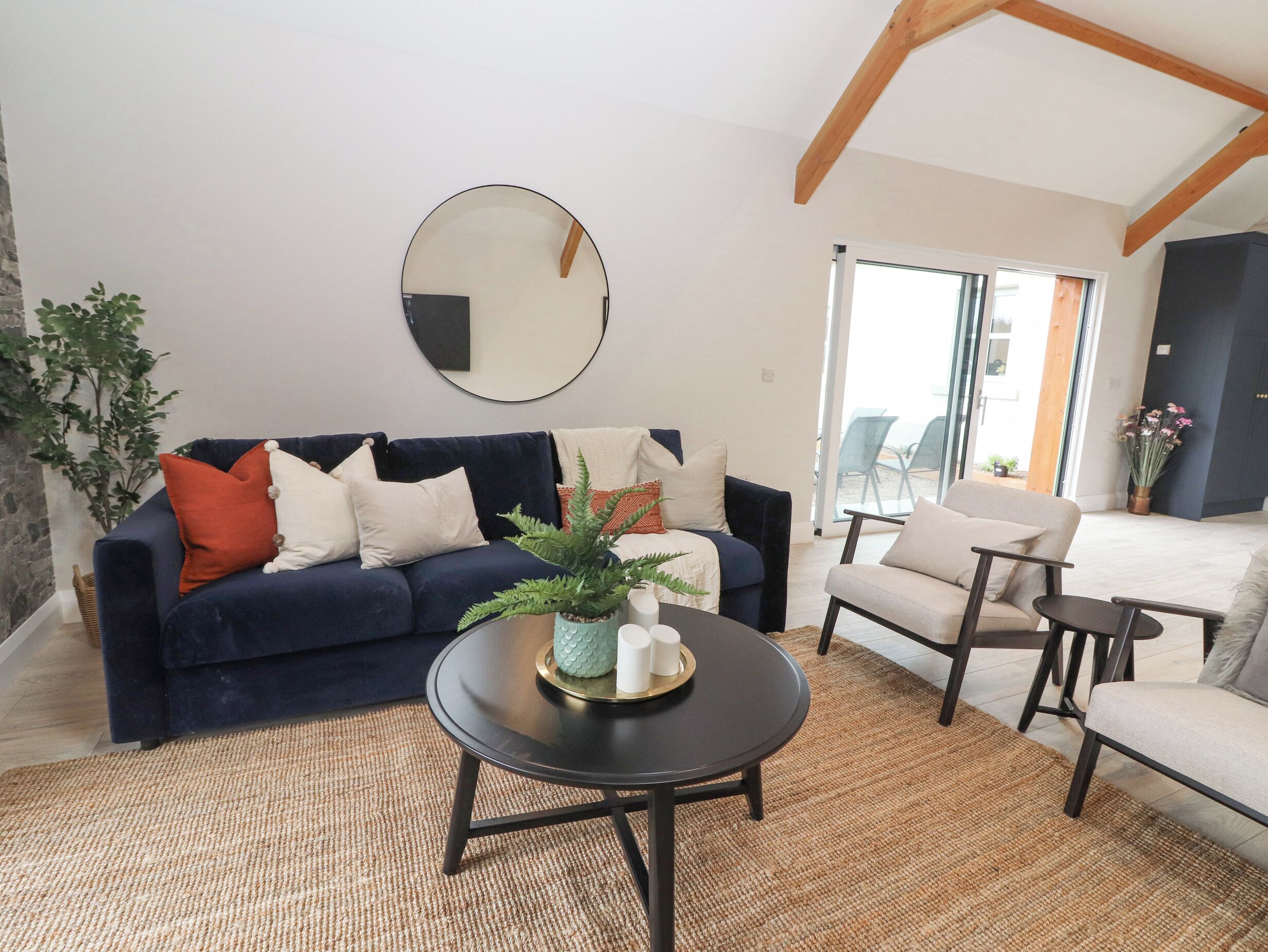 A living room with a dark blue sofa, a round coffee table, and a large mirror on the wall.
