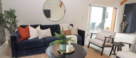 A living room with a dark blue sofa, a round coffee table, and a large mirror on the wall.