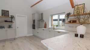 Een moderne keuken met witte kastjes, een groot eiland en een raam dat voor natuurlijk licht zorgt.