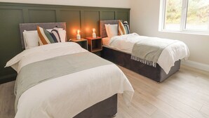 Een slaapkamer met twee bedden, een groot raam en een plafondlamp.