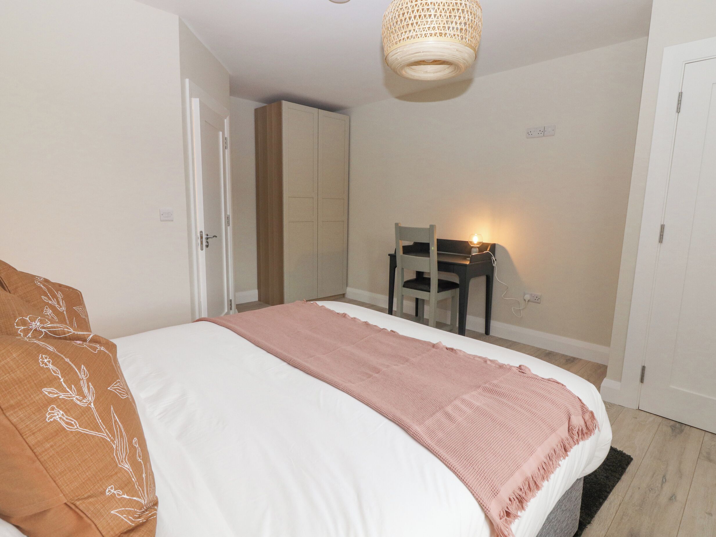 A bedroom with a bed, a desk, and a chair.