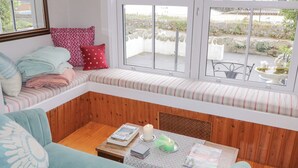 Una habitación acogedora con un banco integrado, una mesa de centro de madera y vistas a una masa de agua a través de amplias ventanas.