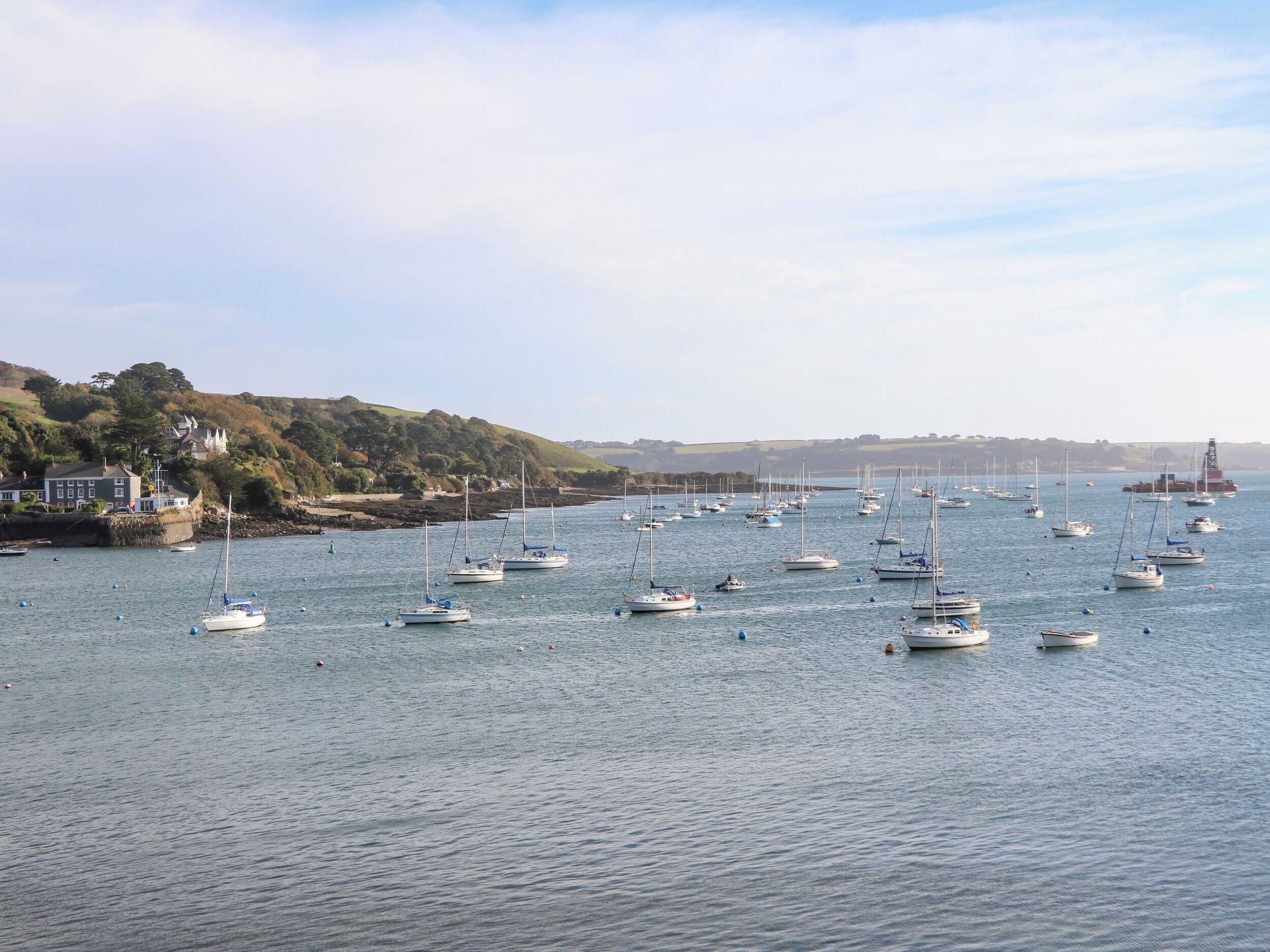 A harbor with multiple boats docked and a lighthouse in the distance.