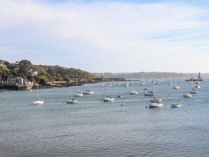 A harbor with multiple boats docked and a lighthouse in the distance.