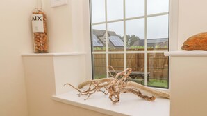 A window sill with a corkscrew bottle, a piece of driftwood, and a wooden object. - Fair View (Truro)