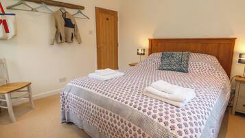 A neatly made bed with a floral-patterned bedspread and a folded towel on top.