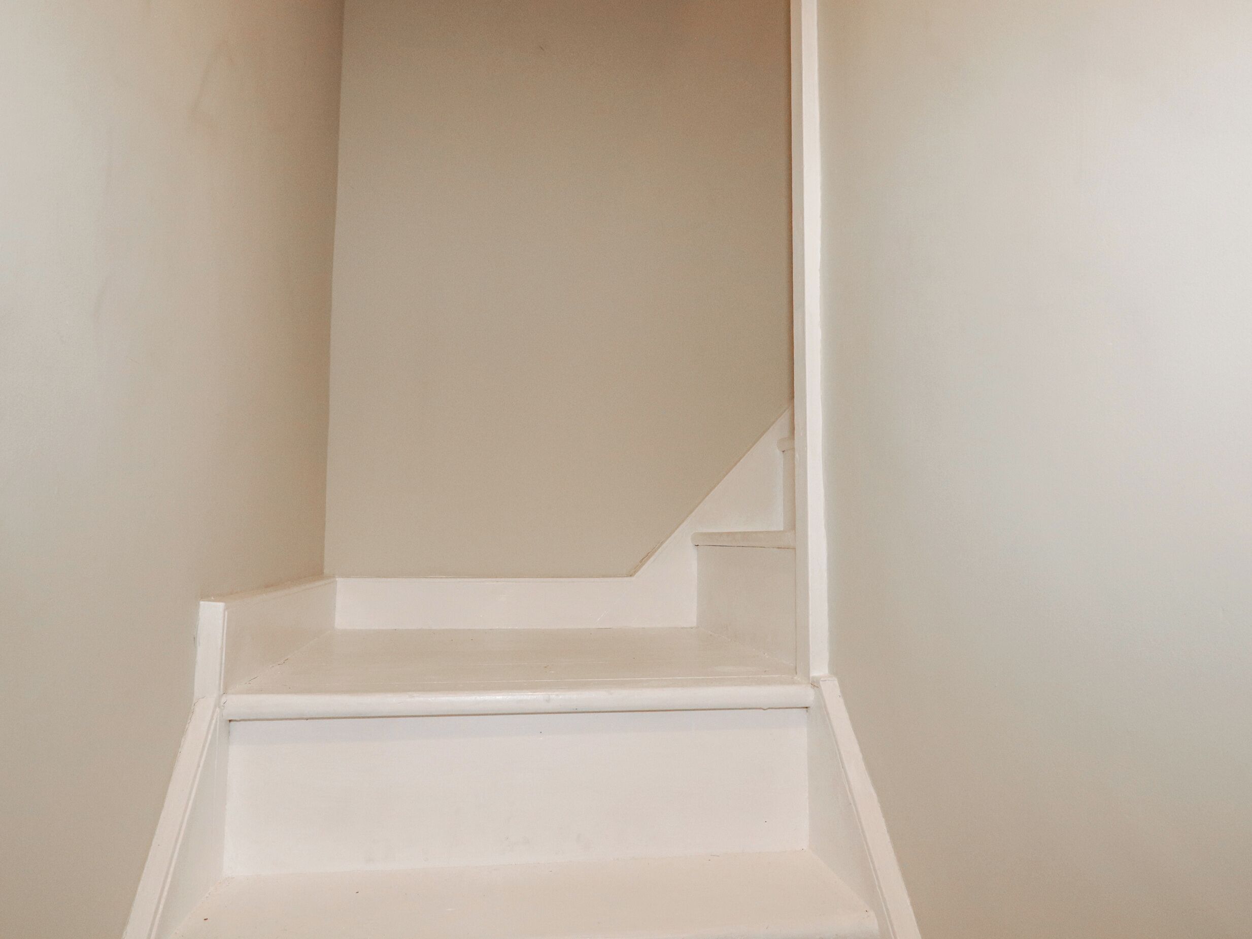 A set of white stairs leading up to a landing.