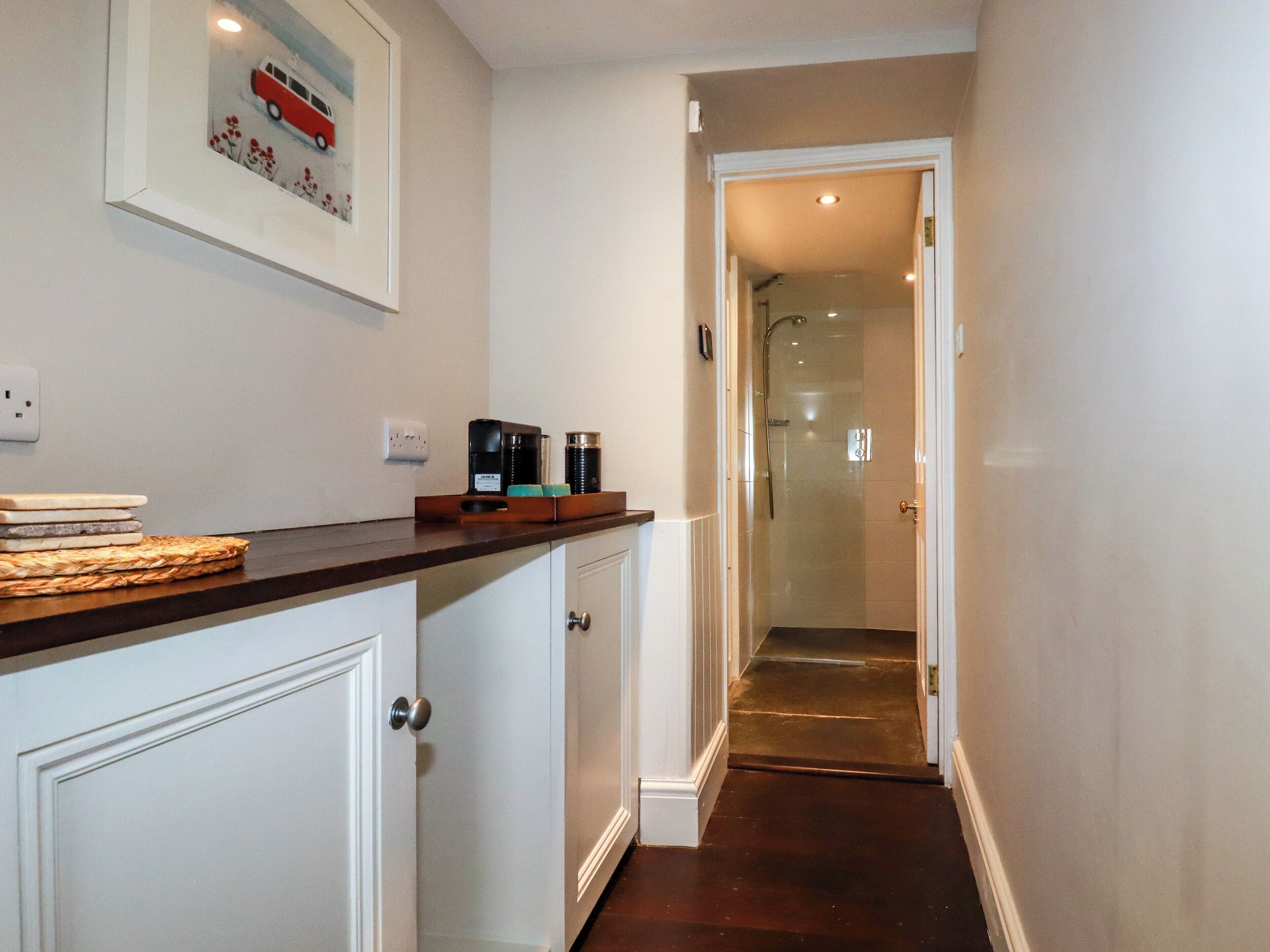 A narrow hallway with a wooden countertop, a coffee maker, and a framed picture on the wall.