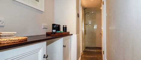 A narrow hallway with a wooden countertop, a coffee maker, and a framed picture on the wall.