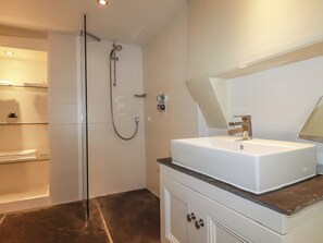 Un baño moderno con ducha acristalada, un lavabo blanco con encimera de mármol y un espejo sobre el lavabo.