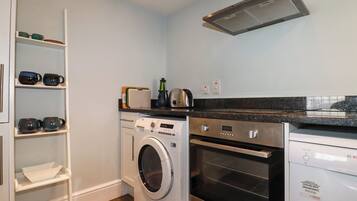 A compact kitchen with a washing machine, oven, and a built-in microwave.