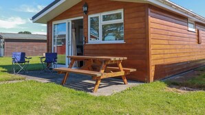 Eine Holzhütte mit Terrasse, Schiebetür und einem kleinen Tisch.