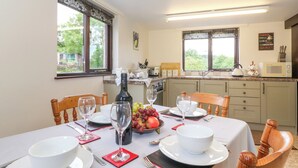 Comedor con una mesa lista para cuatro personas, una botella de vino y un cuenco de fruta.