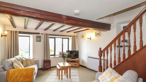 Una sala de estar con un sofá, una mesa de madera, un televisor y una escalera.