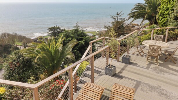 A wooden deck with outdoor furniture overlooking a coastal view. - Seahaze (Torpoint)
