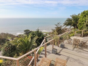 Une terrasse en bois, agréée de mobilier d’extérieur, offrant une vue sur la côte.