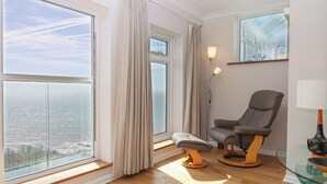A modern room with large windows, a massage chair, and a glass table. - Seahaze (Torpoint)