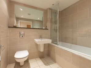 A modern bathroom with a toilet, sink, and shower. - Sea Bleu (St Ives)