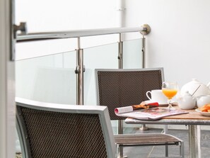 A dining area with a table set for two, featuring a newspaper, a glass of orange juice, a teapot, and a cup. - Sea Bleu (St Ives)