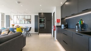 Une cuisine moderne avec des meubles de rangement aux couleurs sombres, un four encastré et une machine à café.