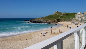 Une plage avec un promontoire rocheux et un bâtiment situé sur une colline.