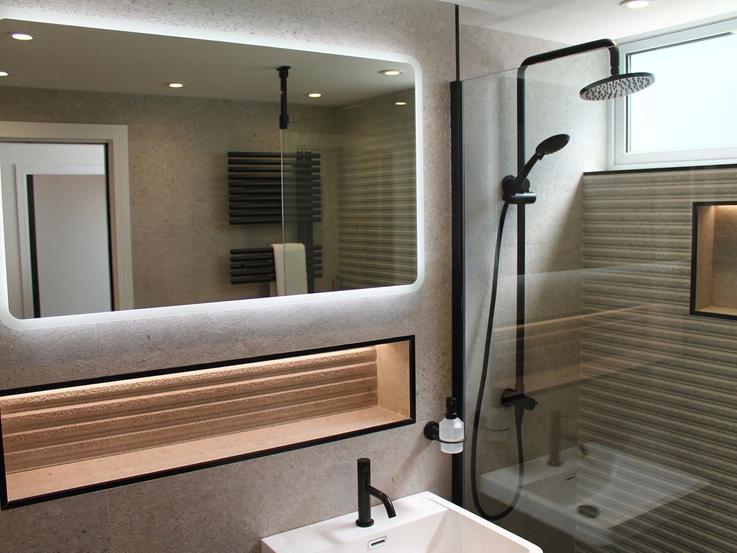 A modern bathroom with a large mirror, a glass shower enclosure, and a built-in sink.