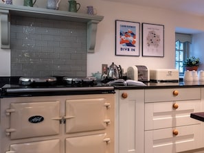 A kitchen with a vintage stove, a toaster, and a kettle on the counter.