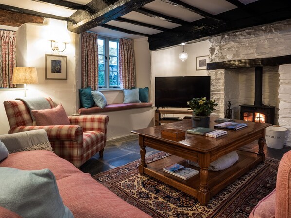 A cozy living room with a fireplace, a sofa, a coffee table, and a television.