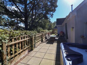 A pathway leading to a building with a barbecue area, a wooden fence, and a large tree. - Seagrass (Bideford)