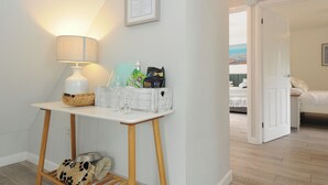 A room with a white table, a lamp, a basket, and a framed menu on the wall.