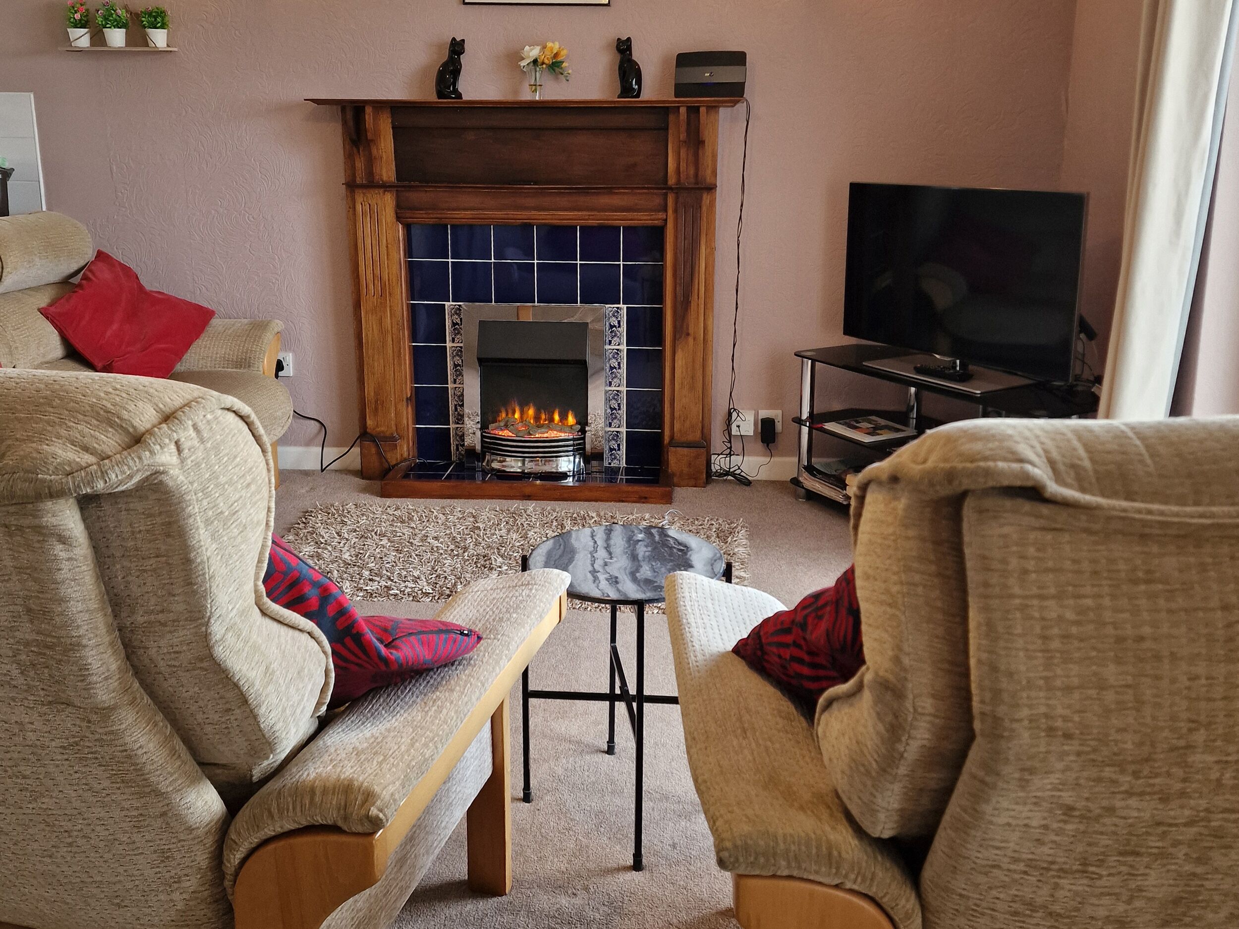 Una sala acogedora con chimenea, asientos cómodos y televisor.