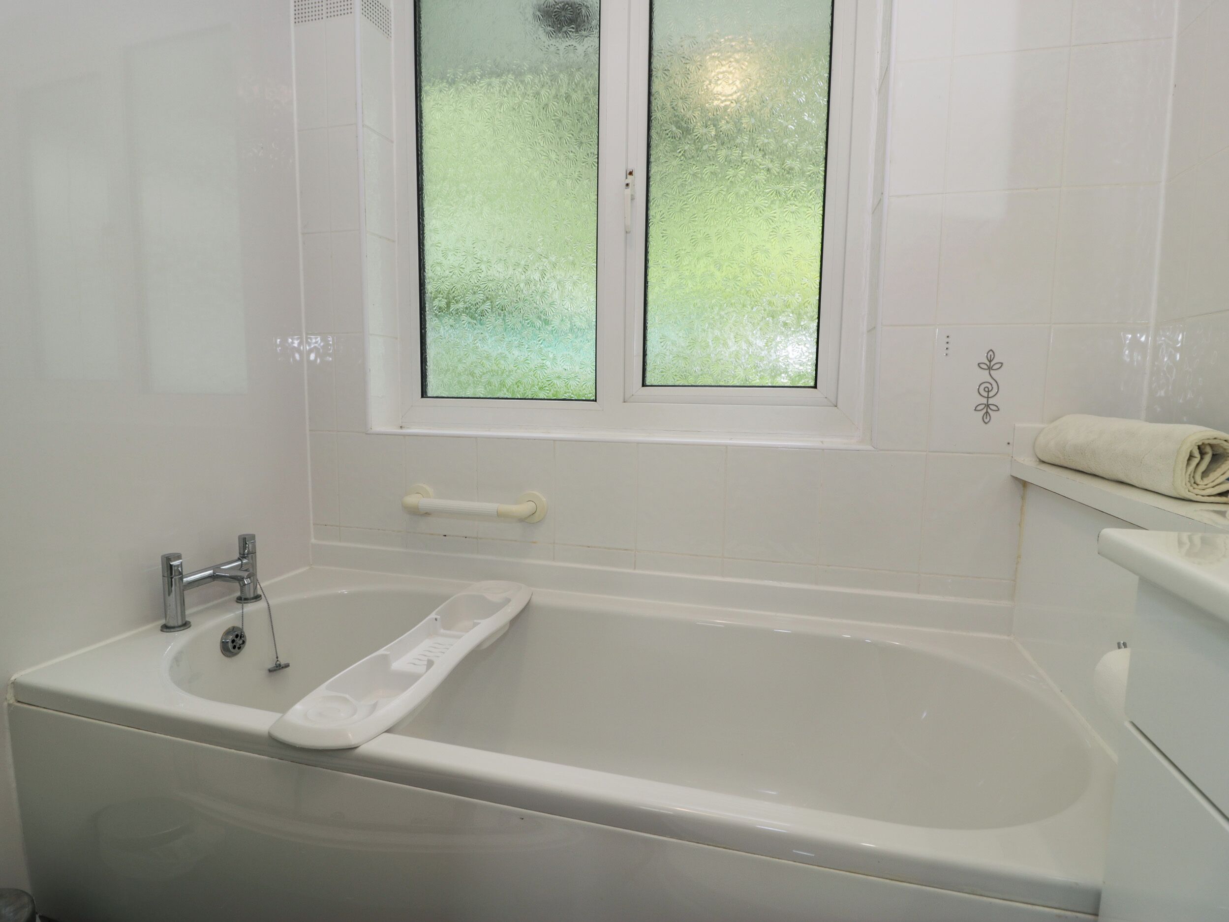 Un baño con bañera, ventana y toallero.