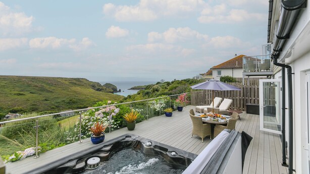Una terraza con jacuzzi, mobiliario exterior y plantas en macetas.