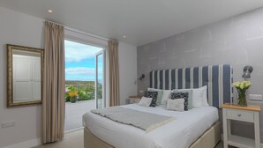 Un dormitorio con una cama grande, una mesita de noche, un espejo y vistas al exterior.