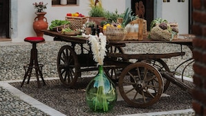 A courtyard with a rustic wooden table, potted plants, and a vintage cart. - L'Angelica Corte Palazzina (Salò)