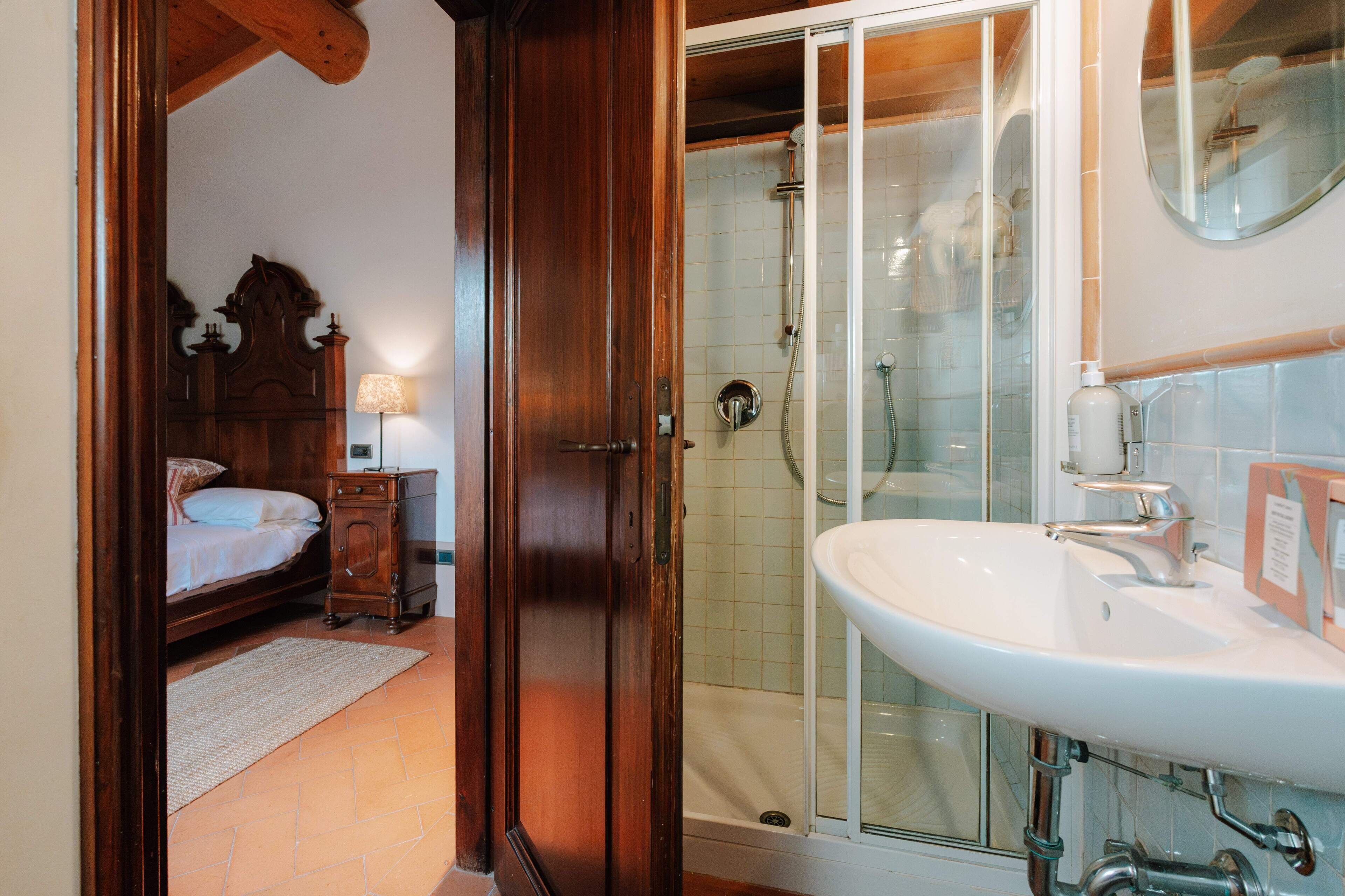 Quarto com cama de madeira, mesa de cabeceira e abajur.
