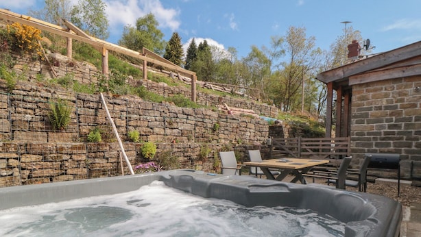 A hot tub with a stone wall and wooden deck in the background. - Thompson Rigg House (Scarborough)