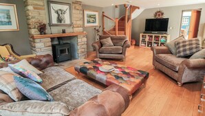 A cozy living room with a stone fireplace, leather sofas, and a colorful ottoman. - Thompson Rigg House (Scarborough)