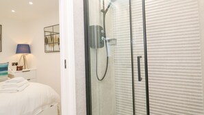 Un baño moderno con ducha de vidrio, una bañera blanca y un perchero para toallas.