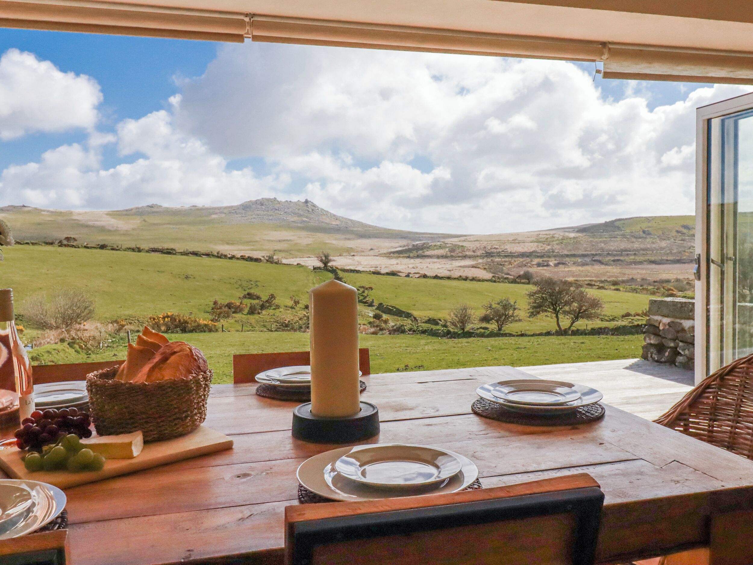 A table set for dining with a view of rolling hills and a clear sky.