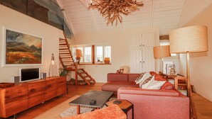 A modern living room with a sofa, coffee table, and a TV on a wooden cabinet. - Roughtor Barn (Camelford)