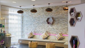 Um spa moderno com uma parede de pedra, um sofá bege com almofadas listradas e duas mesas laterais de madeira.