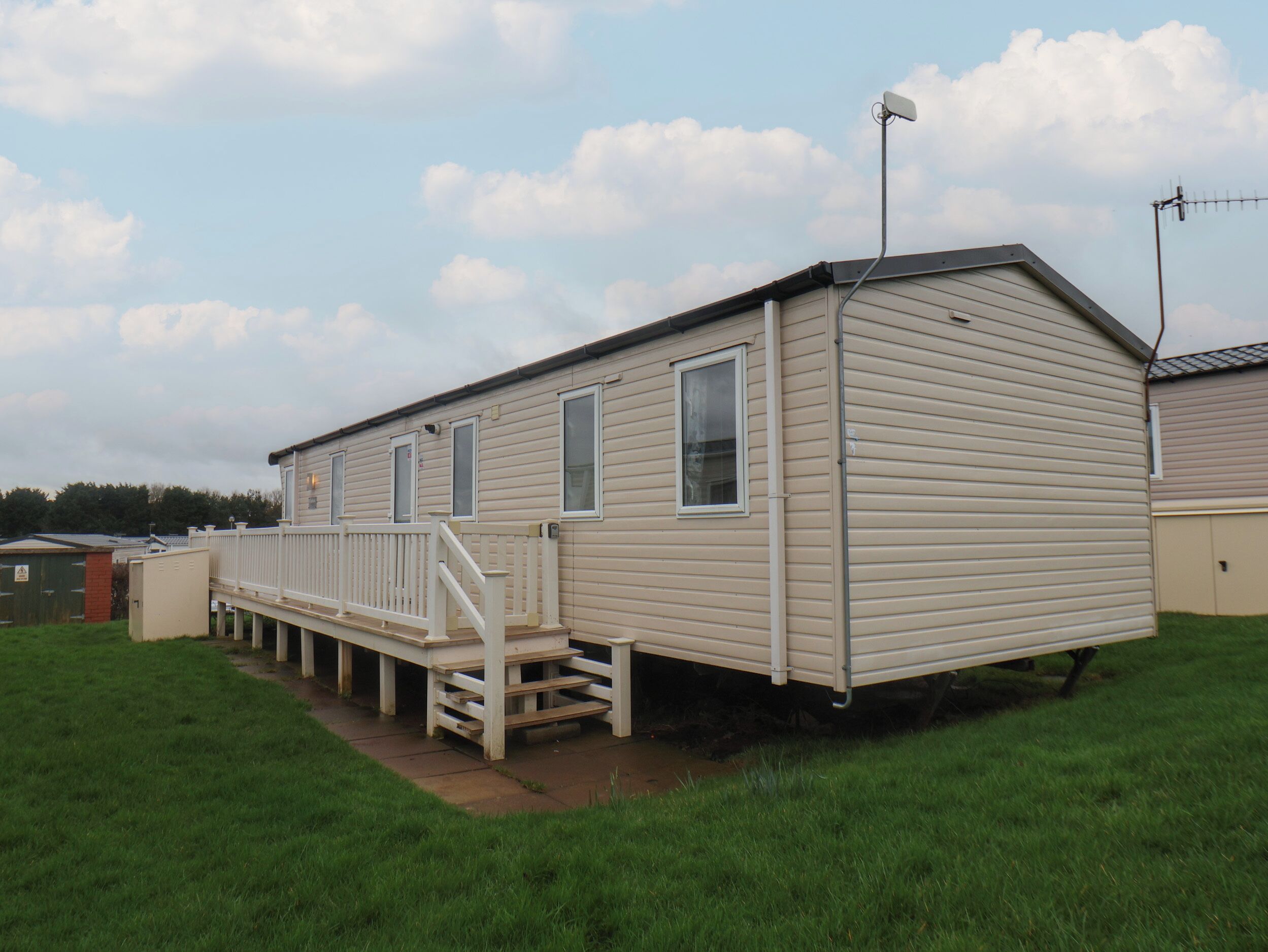 A single-story mobile home with a front porch and a satellite dish.