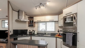 A modern kitchen with a central island, stainless steel appliances, and wooden cabinetry. - 47 The Drake Forgetmeknot (Scarborough)
