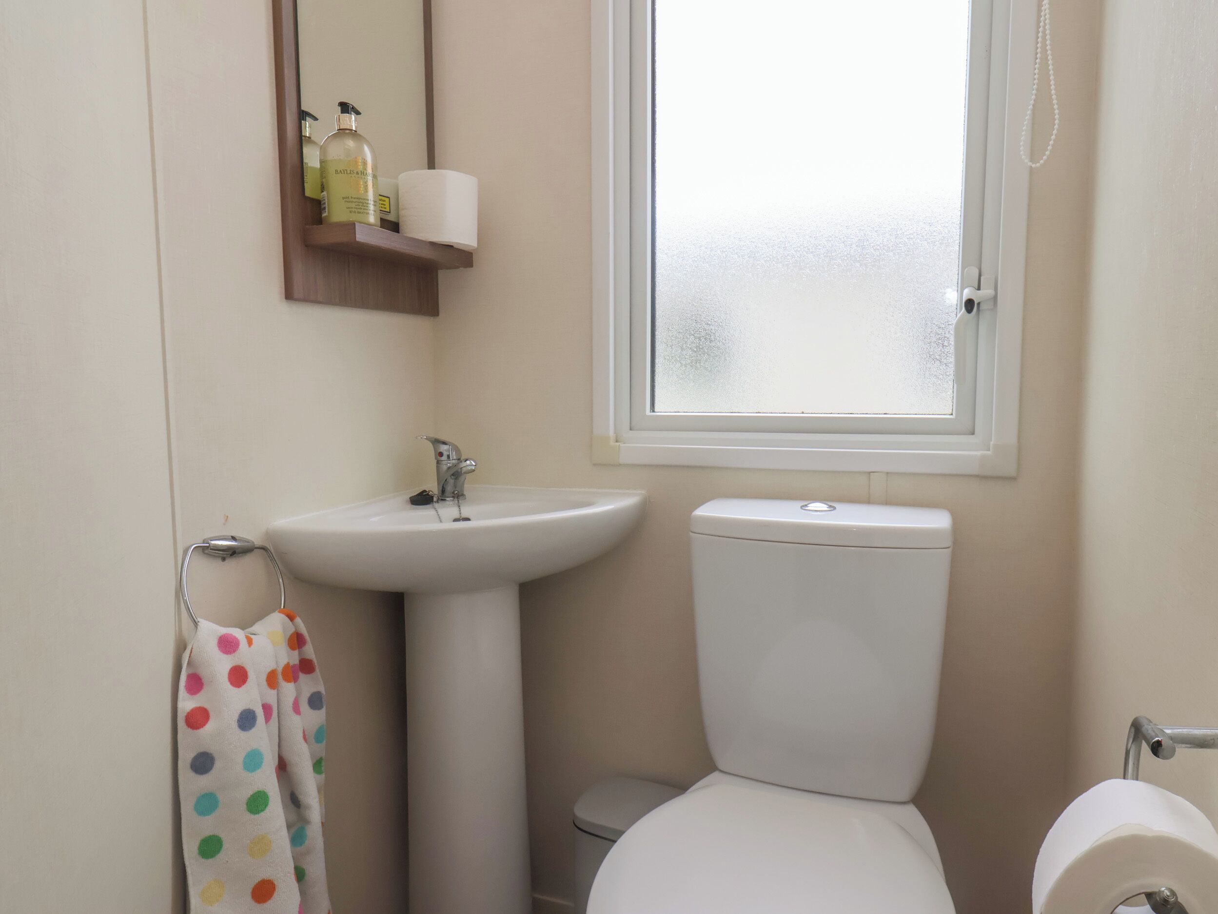Un baño con lavamanos, inodoro y ventana.