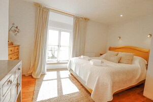 Un dormitorio con cama, cómoda y ventana con cortinas.
