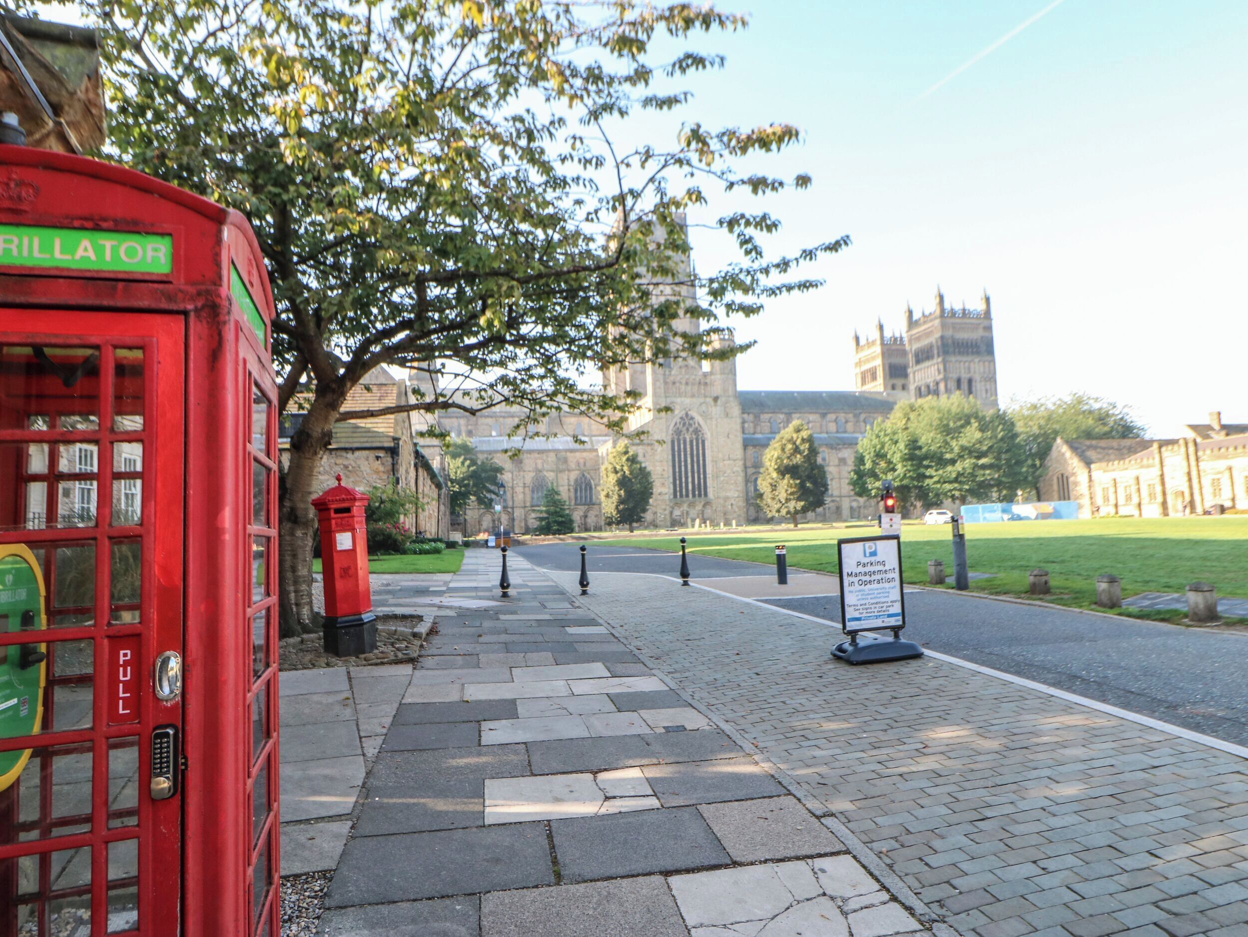 A red telephone booth, a sign for parking management, and a historic building in the background.