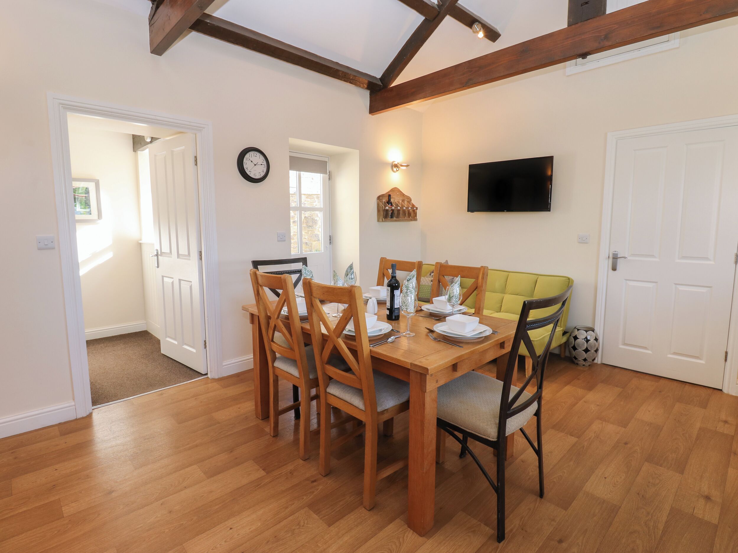 A dining area with a wooden table, chairs, and a yellow sofa.
