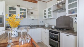 Een moderne keuken met witte kasten, een houten aanrechtblad en een inbouwfornuis.