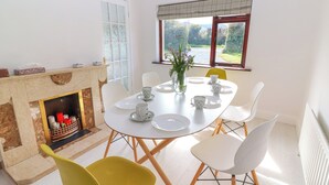 Un comedor con una mesa redonda, sillas blancas y una chimenea.